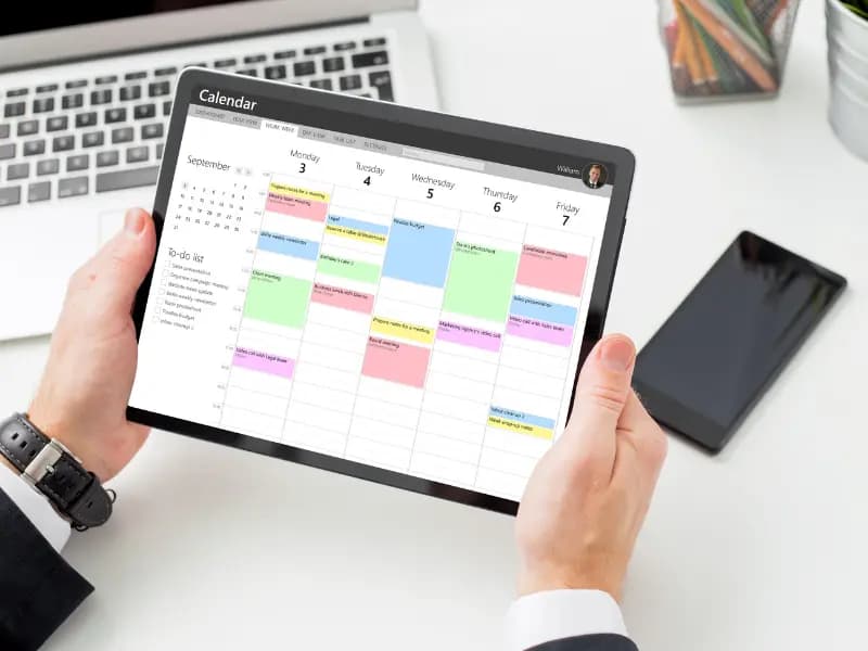 Efficient calendar scheduling displayed on a tablet as a professional reviews a color-coded weekly planner